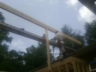 Carpenter setting a ridge beam over a new addition frame — Ice Dam Removal by Roofing Brothers in Pella