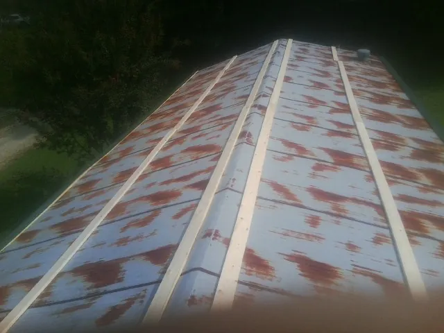 Rusted metal roof panels with new wood purlins before replacement — Storm Damage Roof Repair in Pella by Roofing Brothers