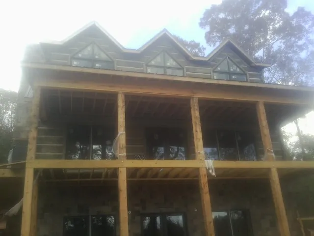 Dormers and porch framing on a large log home under construction — Roof Coating work by our crew in Pella