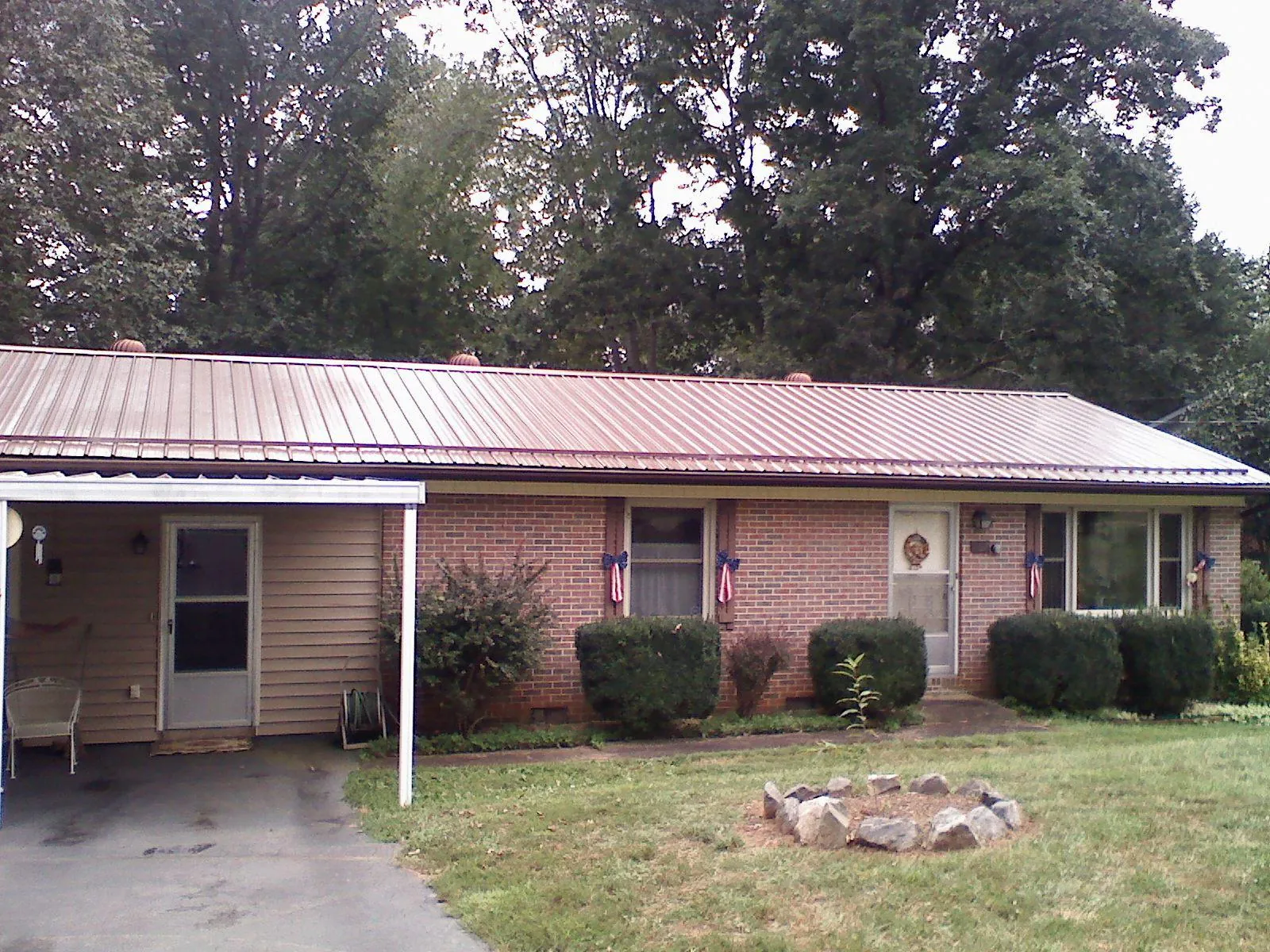 Bronze metal roof and carport on a brick ranch home — Roof Repair work by our crew in Pella