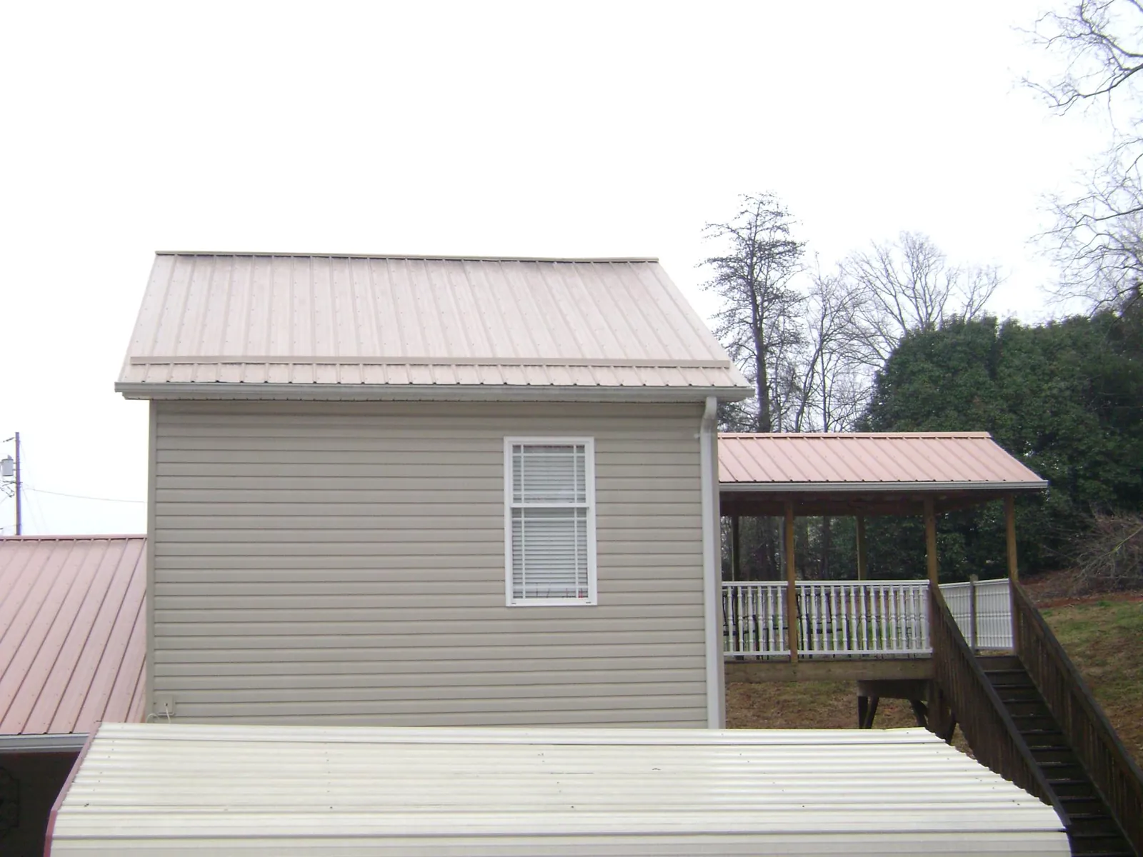 Tan metal roofs on a two story addition and attached porch, from a Roof Replacement job in Pella